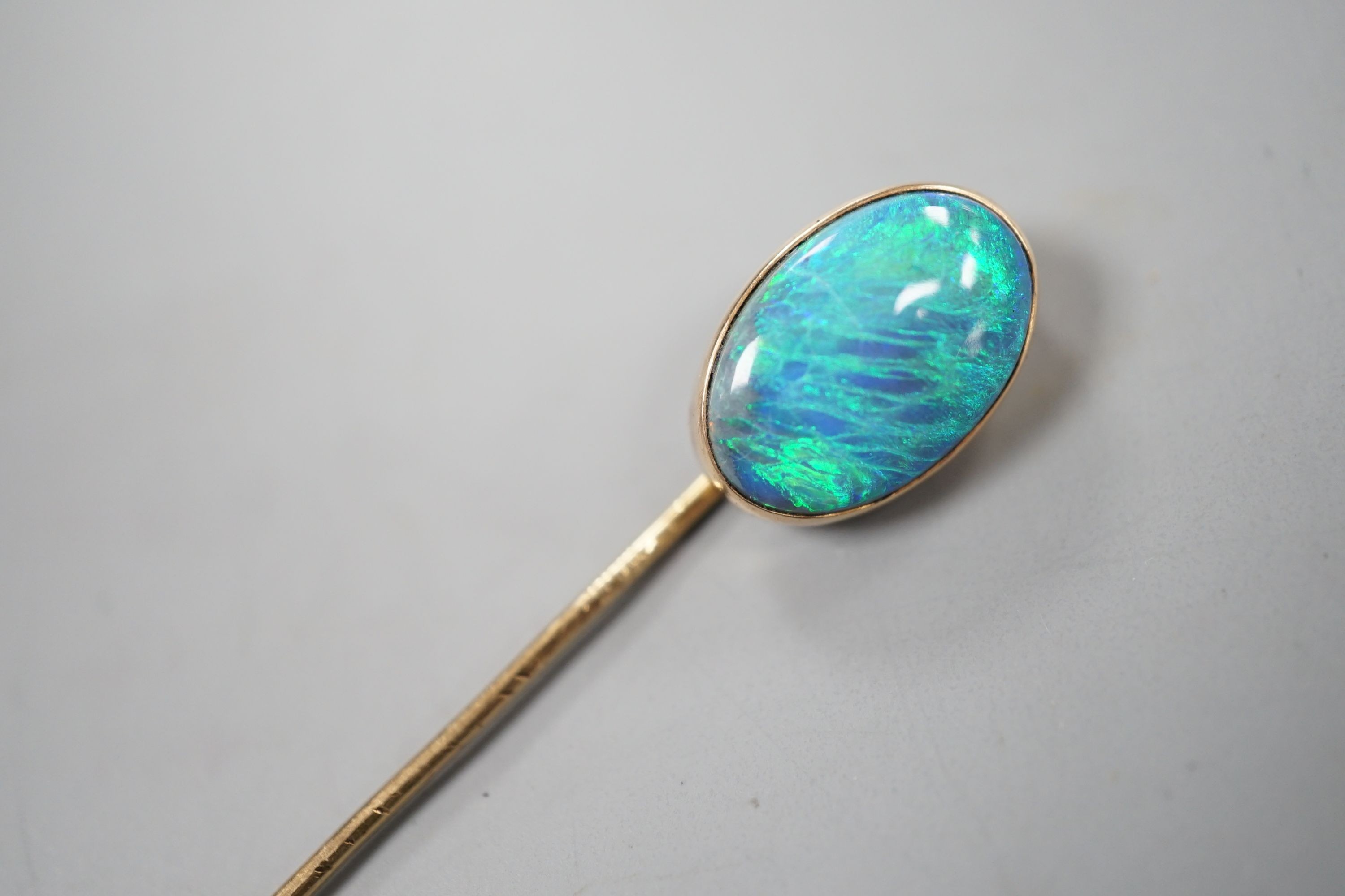 An Edwardian yellow metal and oval black opal set stick pin, 67mm, gross 2.7 grams